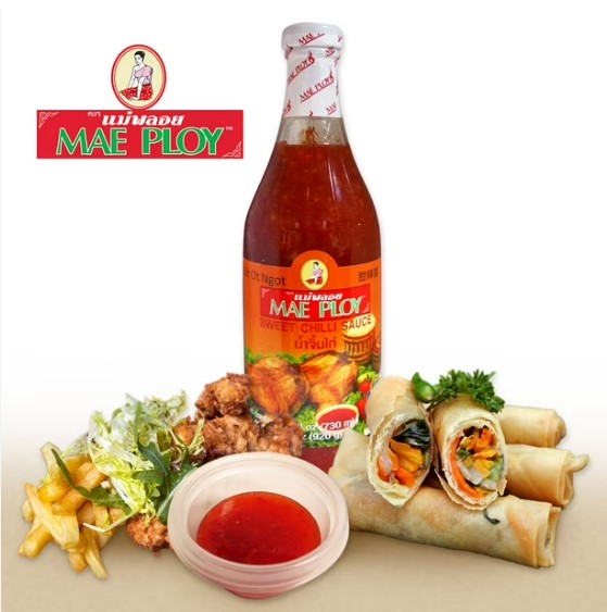 Bottle of Mae Ploy sweet chili sauce with visible chili flecks, served beside fried spring rolls